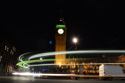 Light trails on bridge with illuminated big ben in background at night