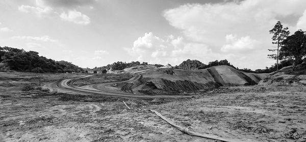 Panoramic view of road amidst field against sky