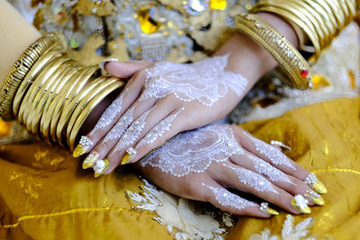 Midsection of woman with heena tattoo on hands