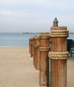 Wooden posts on beach against sky