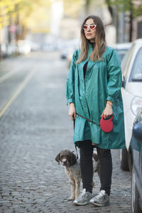 Smiling woman standing with dog on street in city