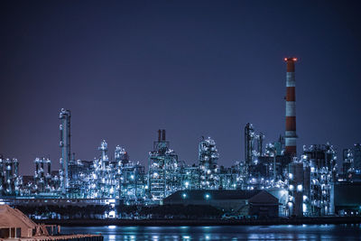 Illuminated factory against sky at night