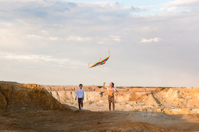 Children run holding flying kite by the fishing line.