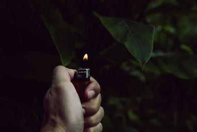 Close-up of hand holding lit candle