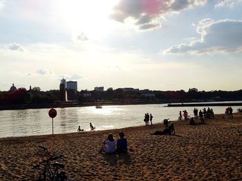 People on beach against sky during sunset