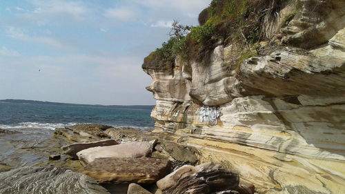 Rock formation by sea against sky