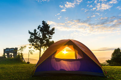 Tent on landscape against sky during sunset