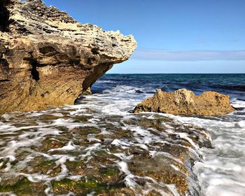 Rock formation in sea against clear sky