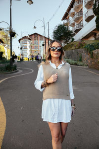 Young woman wearing sunglasses standing on street in city
