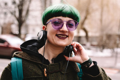 Portrait of happy non-binary hipster standing on city street