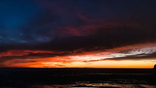 Scenic view of sea against dramatic sky during sunset