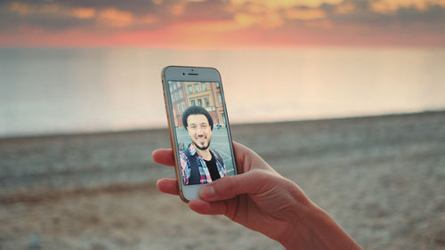 Woman video conferencing at beach during sunset