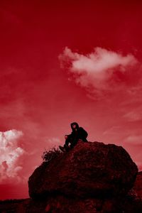 Silhouette man standing on rock against sky