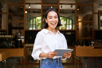 Portrait of young woman standing in cafe