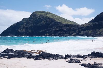 Scenic view of sea by mountains against sky
