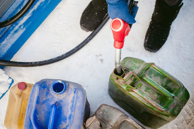 Low section of man filling can with fuel during winter