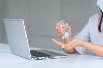 Midsection of woman using laptop on table