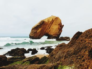 Rock formation on beach against sky