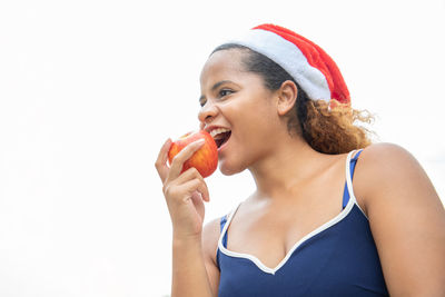 Portrait of woman eating apple against white background