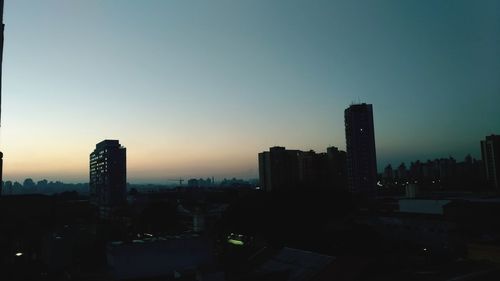 Buildings in city against clear sky during sunset