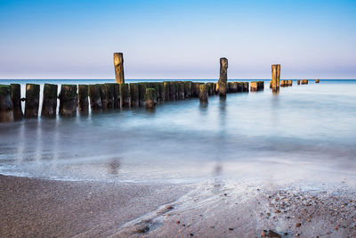 Wooden posts on beach against sky