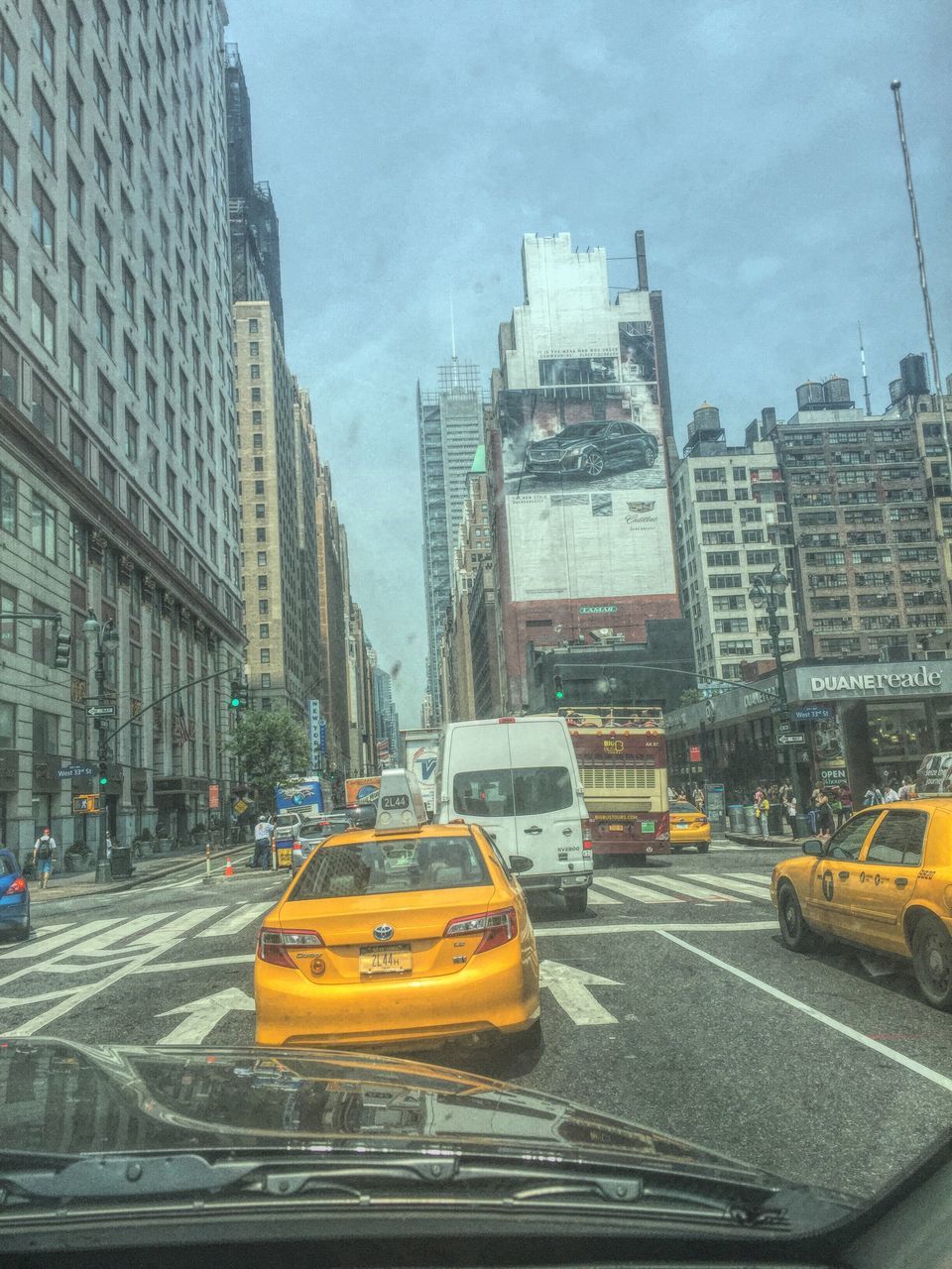 transportation, mode of transport, car, land vehicle, building exterior, city, architecture, built structure, street, yellow, road, traffic, on the move, city street, city life, sky, travel, road marking, outdoors, vehicle