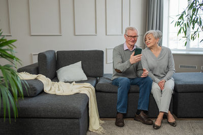 Young woman using laptop while sitting on sofa at home