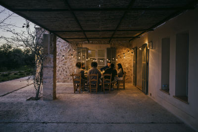 Male and female friends sitting at dining table in patio during dinner party