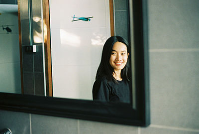 Portrait of a smiling young woman standing against window