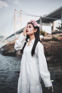 Portrait of young woman standing against sky