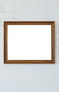 Wooden photo frame on the white room wall inside the building