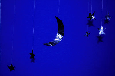 Low angle view of birds flying against blue sky