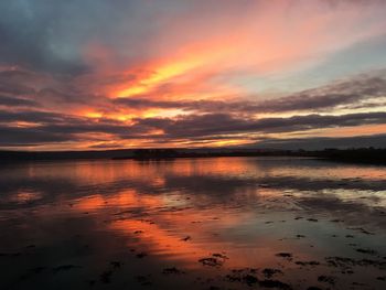 Scenic view of sea against dramatic sky during sunset