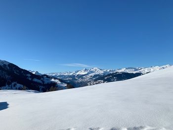 Scenic view of snowcapped mountains against clear blue sky