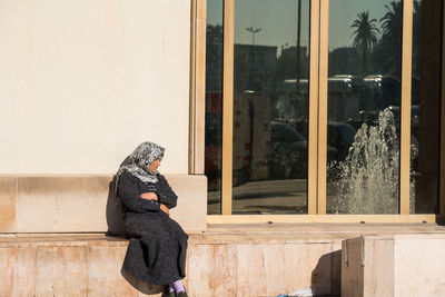 Side view of woman using mobile phone at window