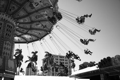 Low angle view of people at amusement park against sky