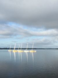 Boats in sea against cloudy sky