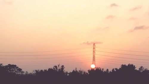 Silhouette electricity pylon against sky during sunset