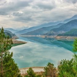 Scenic view of lake and mountains against cloudy sky