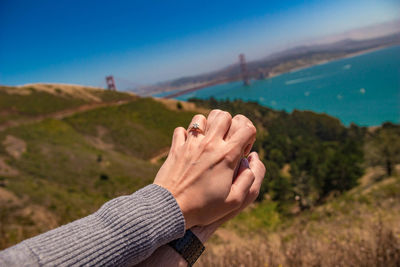 Cropped image of couple with holding hands against mountains