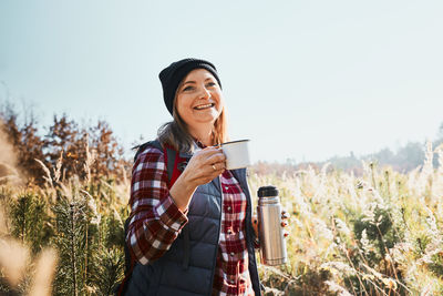 Smiling woman relaxing and enjoying the coffee during trip. woman with backpack hiking in mountains