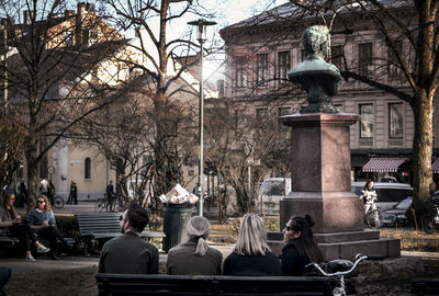 Man sitting on sculpture in city