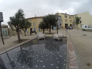 Wet street in city against sky