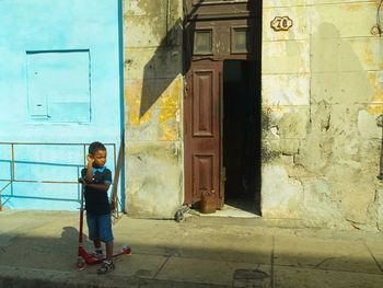 Full length of boy on sidewalk by building