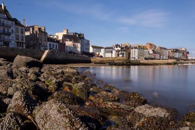 Buildings by sea against sky