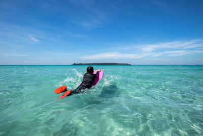 Boy surfboarding in sea against sky