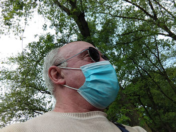 Low angle view of man wearing sunglasses against trees