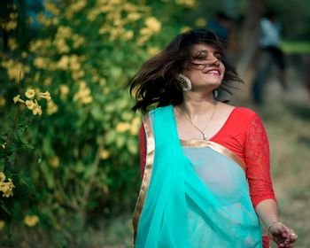 Portrait of cheerful woman tossing hair at park