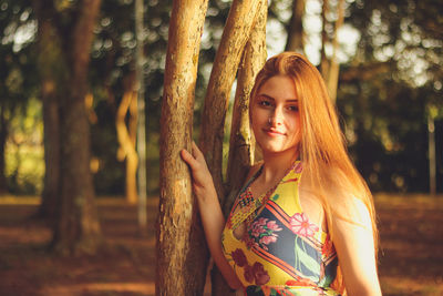 Beautiful woman standing by trees in forest