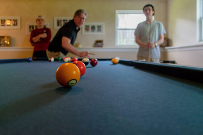 Men playing pool with sons at home